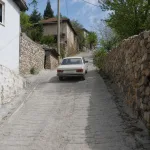 A car drives uphill on a steep village road.