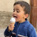 A child licks an ice cream cone.
