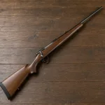 An unloaded hunting rifle shown as a neutral object on a table.