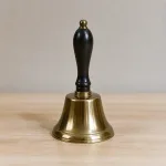 Single metal hand bell on a simple tabletop.