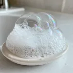 Soap foam and translucent bubbles on a simple bathroom surface.