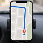 A phone navigation app in a car holder marking a destination point on the road, communicating stop here.